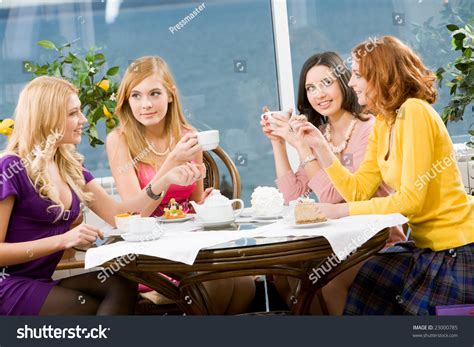 Portrait Of Four Young Women Sitting At The Table In The Cafe Stock