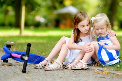 Girl Comforting Her Sister After She Fell Stock Photo By ©mnstudio