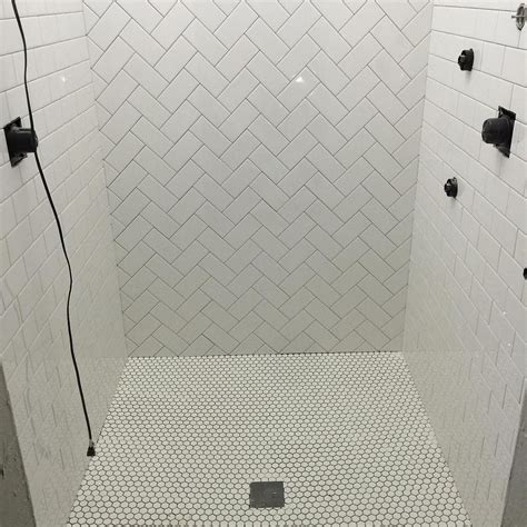 classic subway tile with a herringbone design and penny rounds on the floor of this shower in