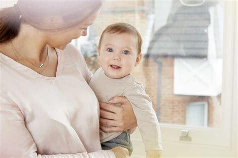 Portrait Of Baby Boy Being Carried By Mother At Home Stock Photo