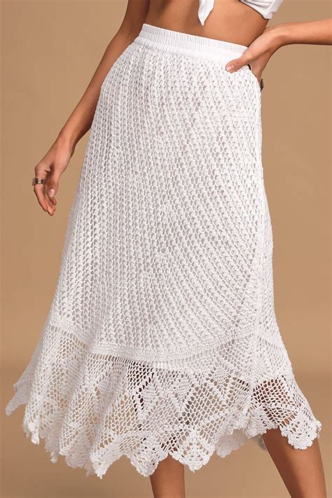 A Woman Wearing A White Crochet Skirt And Crop Top With Her Hands On