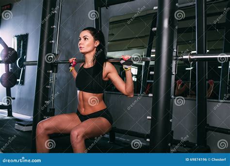 Sportsy Woman Doing Squats With A Barbell In Smith Machine Stock Photo