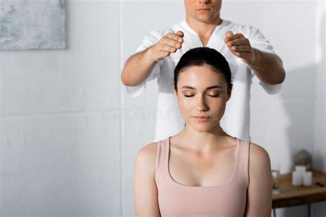 Healer Standing Near Woman On Massage Table And Holding Hands Above Her