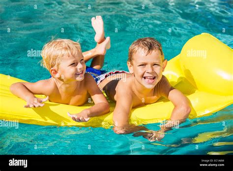 Young Kids Having Fun In Swimming Pool On Yellow Raft Summer Vacation