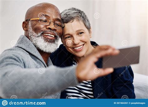 pose for the camera sweetheart an affectionate senior couple taking selfies while relaxing on