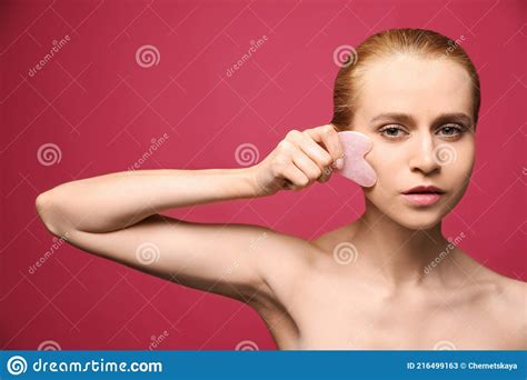 Belle Jeune Femme Faisant Le Massage Du Visage Avec L Outil Gua Sha Sur Fond Rose Image Stock