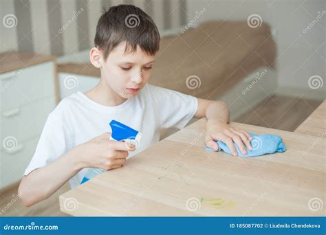 A School Aged Boy Cleans The Room Puts Detergent On The Table In His