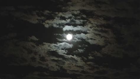 Dark Clouds Slowly Moving Through The Full Moon Shining