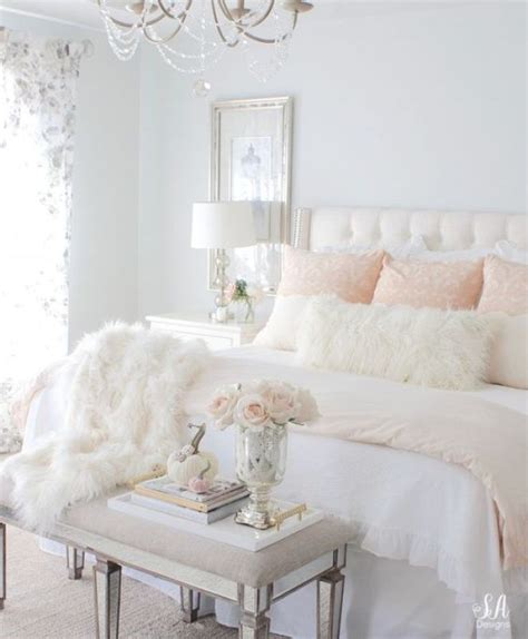 A bright feminine bedroom with a cnaopy bed, a wooden bench and a woven chair, a statement plant and a floral chandelier. Feminine bedroom ideas for more peace and romance in the ...
