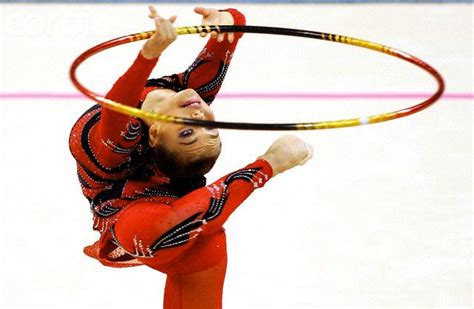 A Woman Is Performing With A Hula Hoop In The Air While Wearing Red And