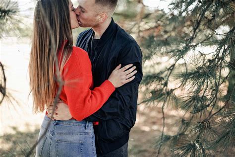 People Couple Kissing Beside Green Leaf Trees During Daytime Person Image Free Photo