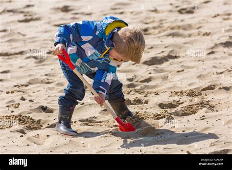 Bournemouth Young Boy Digging In Sand With Spade At Bournemouth Beach