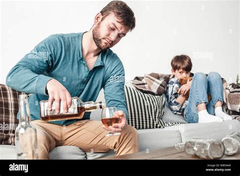 Boy And Father Alcoholic At Home Man Pouring Whiskey Into Glass