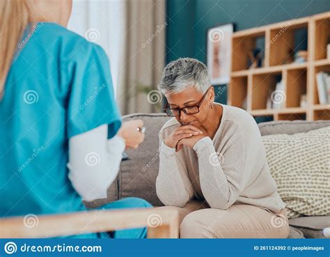 Talking Healthcare And Nurse With Sad Old Woman In Home Sitting On