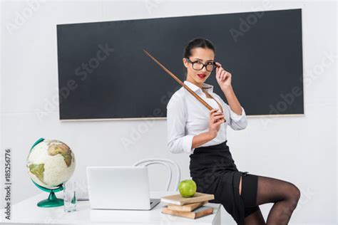 Young Sexy Teacher In Stockings With Pointer Sitting On Desk In Front