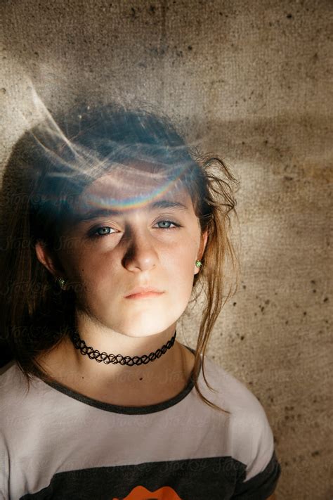 Girl With Serious Expression And Rainbow Flares Over Her Head Looking