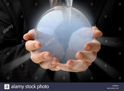 Businessman Holding A Glowing Crystal Ball In Both Hands Stock Photo
