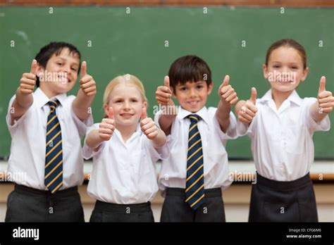 Smiling Students In School Uniforms Giving Thumbs Up Stock Photo Alamy