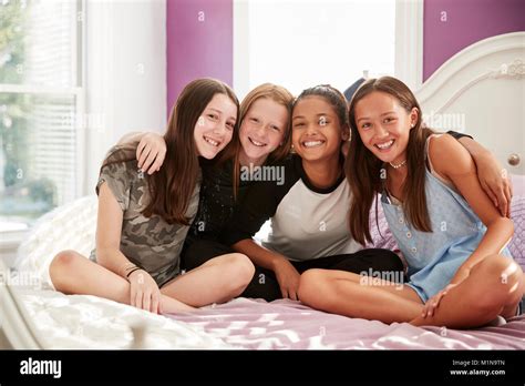 Four Teen Girls Sitting On Bed Looking At Camera Close Up Stock Photo