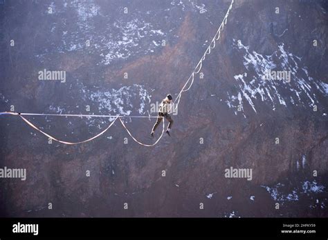 An Athlete Climbing To A Highline To Gain A Foothold High Over A