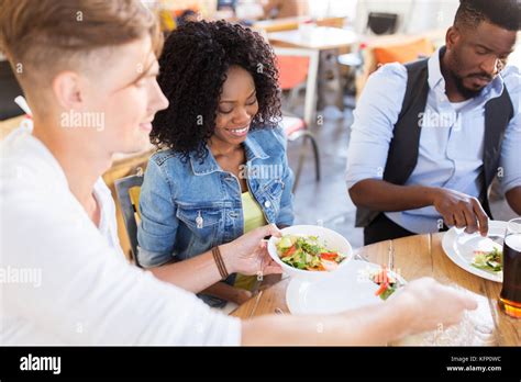 Happy Friends Eating And Talking At Restaurant Stock Photo Alamy