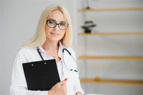 Female Doctor Wearing Lab Coat And Stethoscope And Holding Clipboard In