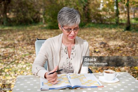 Older Woman Sitting In The Park And Solves Sudoku Stock Photo