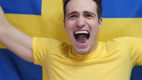 Swedish Young Man Celebrating While Holding The Flag Of Sweden In Slow