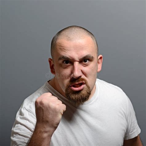Portrait Of A Angry Man Holding Fists Against Gray Background Stock