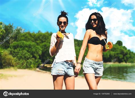 Two Cool Trendy Hipster Twin Girls With Cocktails At The