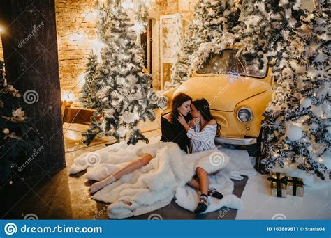 Lesbian Couple Hugs Against Background Of Christmas Decorations And Retro Car Stock Image