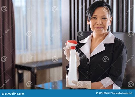 empregada doméstica asiática positiva do hotel que guarda um utensílio de limpesa foto de stock