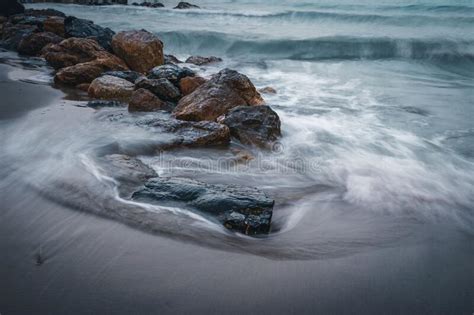 Long Exposure Effect Of Ocean Waves Hitting The Sandy Beach With Stones