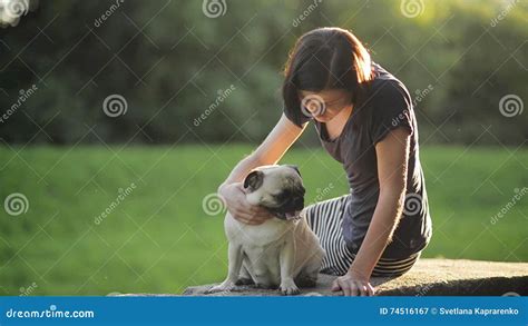 Young Beautiful Girl Stroking Her Dog In A Park At Sunset Woman