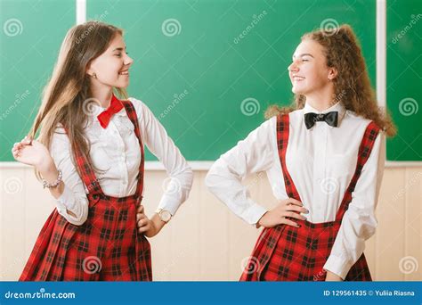 Zwei Lustige Schulmädchen In Der Schuluniform Stehen Mit Büchern Auf