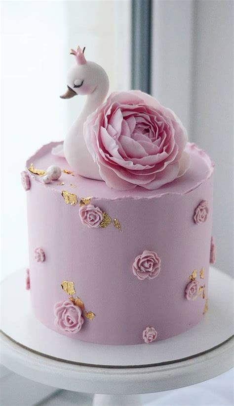 A Pink Cake Decorated With Flowers And A White Swan