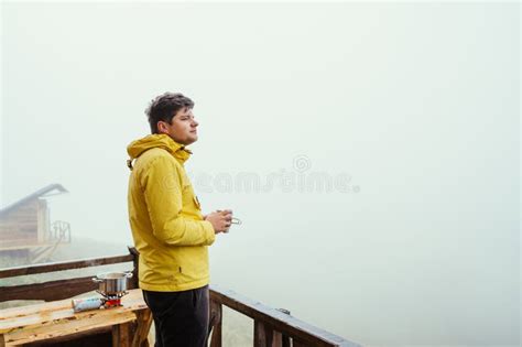 A Male Tourist Stands In The Morning With A Cup Of Tea In His Hands On