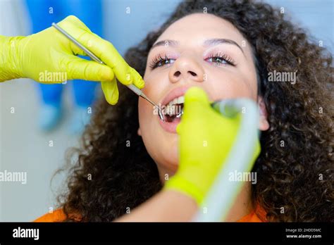 Beautiful Mixed Race Teenage Girl Having Tooth Drill Procedure At Dental Office Hands In Green
