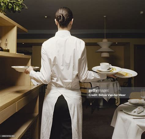Waitress Carrying Dirty Plates In Restaurant Rear View High Res Stock