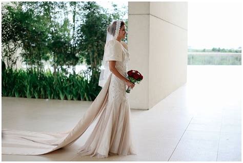 A Woman In A Wedding Dress Holding A Bouquet And Looking Away From The Camera While Standing