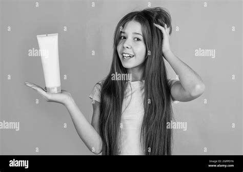 Cheerful Kid Girl With Long Straight Hair Hold Conditioner Shampoo Or