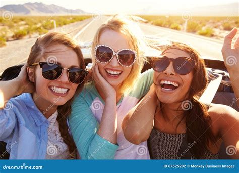 Three Female Friends On Road Trip In Back Of Convertible Car Stock