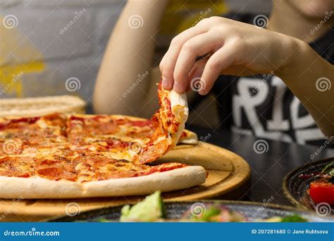 Hand Taking Slice Of Pepperoni Pizza From Round Wooden Tray Stock