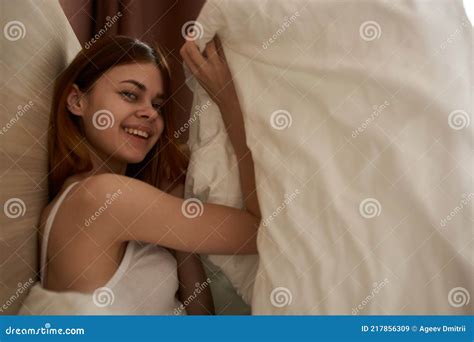 cute woman tied up under blanket in bed in the morning near window cropped view stock image