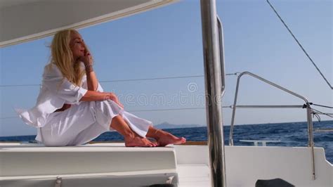 Woman Relaxing On A Cruise Catamaran Sail Boat Wearing White Summer