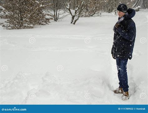 Teenager Boy Stands In Deep Snow Under A Heavy Snowfall Stock Photo