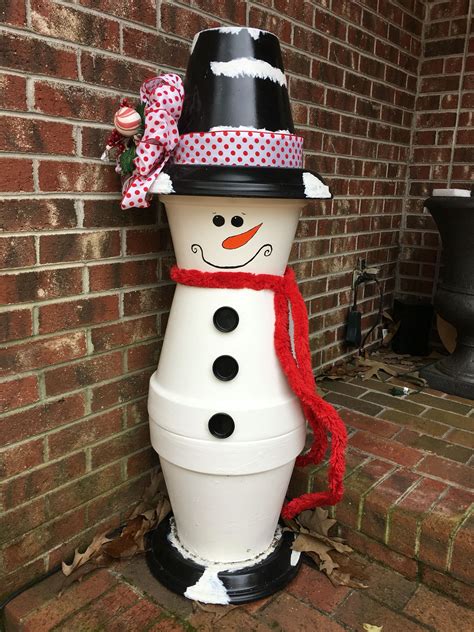 A Snowman Made Out Of Plastic Buckets Sitting In Front Of A Brick Wall