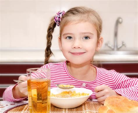 Cute Smiling Little Girl Having Breakfast Cereals With Milk Stock Photo