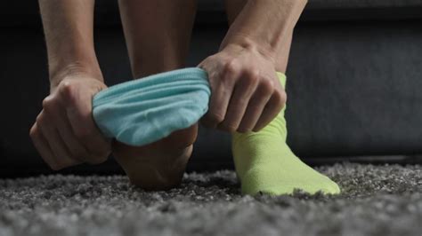 Close Up Of Womans Hands Putting On Mismatched Socks Of Different Color On Her Feet Woman