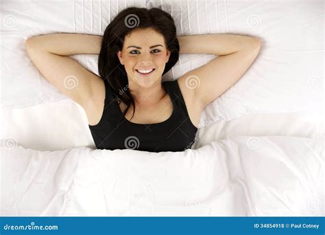 woman laid in bed relaxed looking up at the camera smiling
